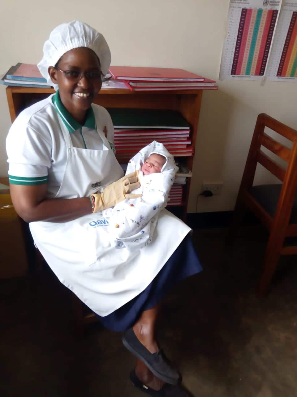 Sister Jacinta weighing an infant as a way of monitoring growth during an immunization outreach