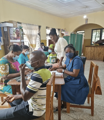 Sister Comfort (blue dress) at Holy Child Catholic hospital in Ghana attending to people with diabetes and hypertension at the Public Health Unit